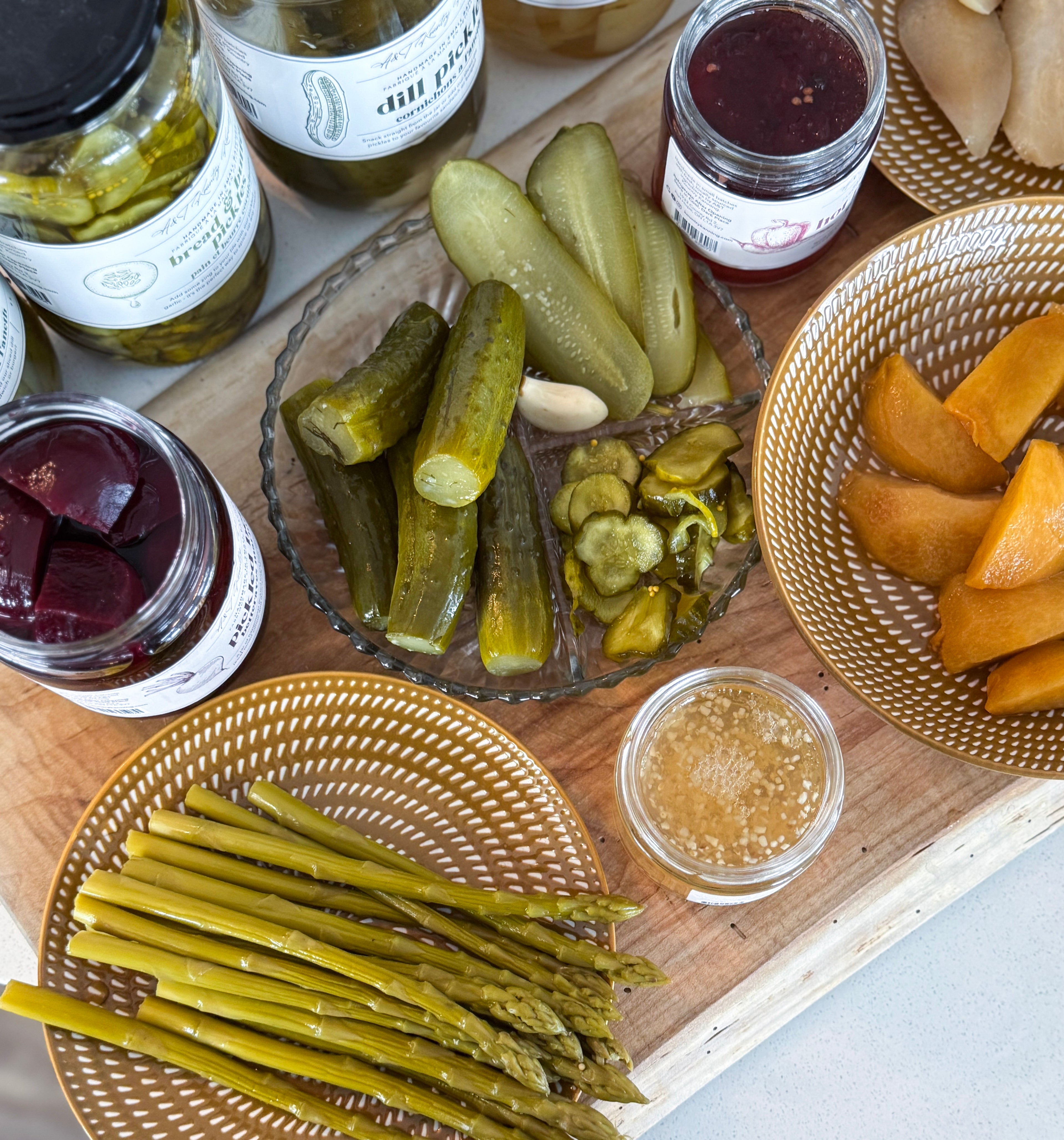 Assorted pickled vegetables and condiments on a wooden board.