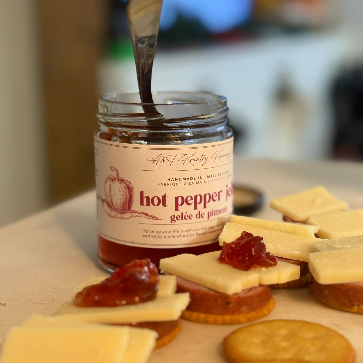 Jar of hot pepper jelly with crackers and cheese on a table.